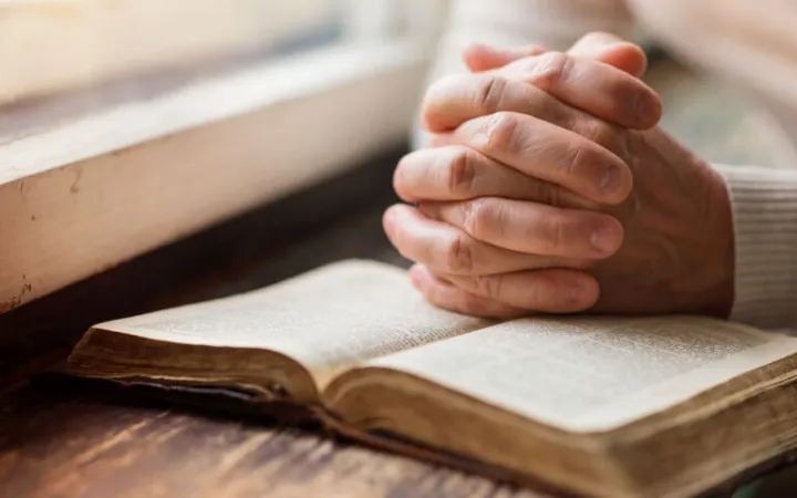 hands in prayer on bible