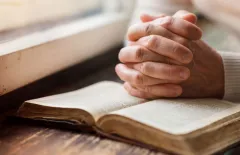 hands in prayer on bible